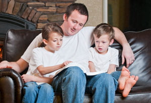 father reading a book with sons