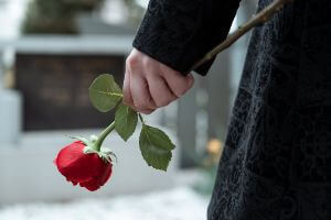 holding rose in front of grave