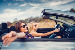 female teens driving a convertible in summer weather